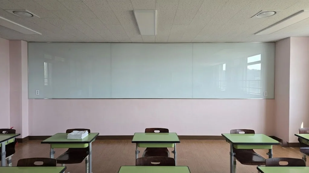 쾌적한 교육 공간을 위한 화이트 백페인트글라스 시공 교실 벽면 전체를 화사하게 밝혀주는 화이트 백페인트글라스 정면 모습으로, 우수한 지움성과 내구성을 자랑합니다.