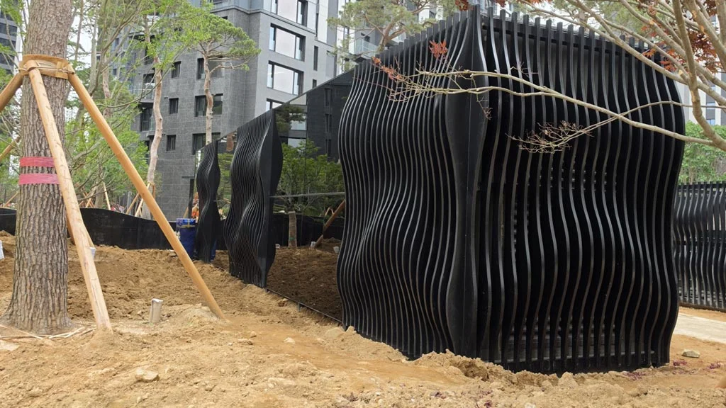 조경 산책로 블랙 백페인트글라스 시공 아파트 산책로를 따라 유려하게 이어지는 조경 구조물에 블랙 백페인트글라스를 정밀하게 부착한 시공 현장.