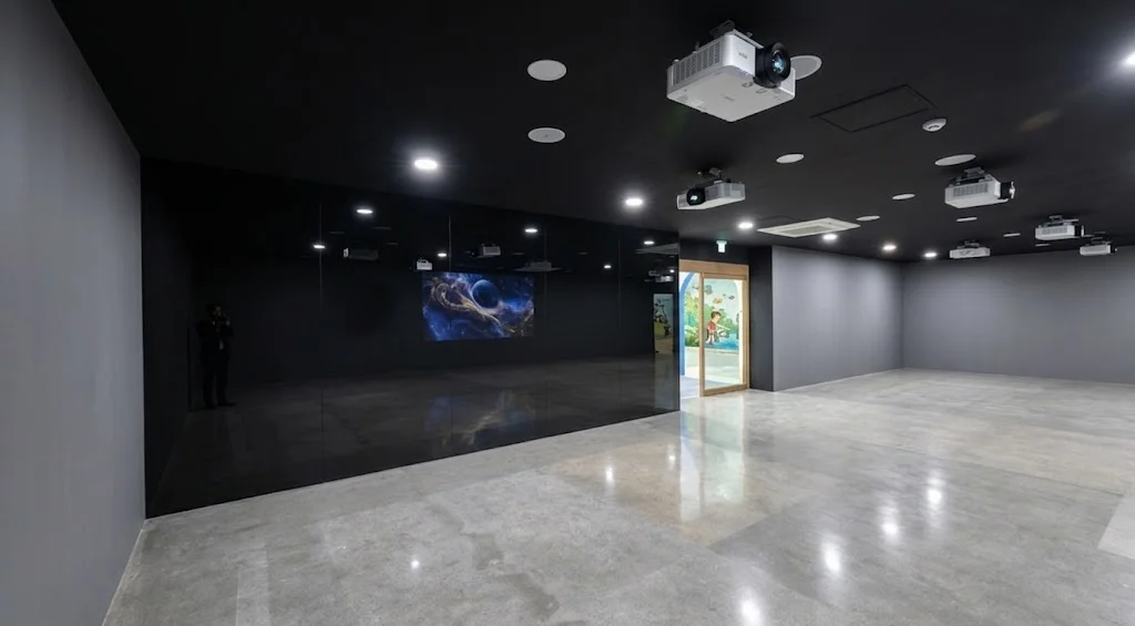출입구 동선과 조명의 각도를 정밀하게 계산하여 왜곡 없이 시공된 충북 곤충박물관 전시실 내부의 전면 흑경 부착 사진.